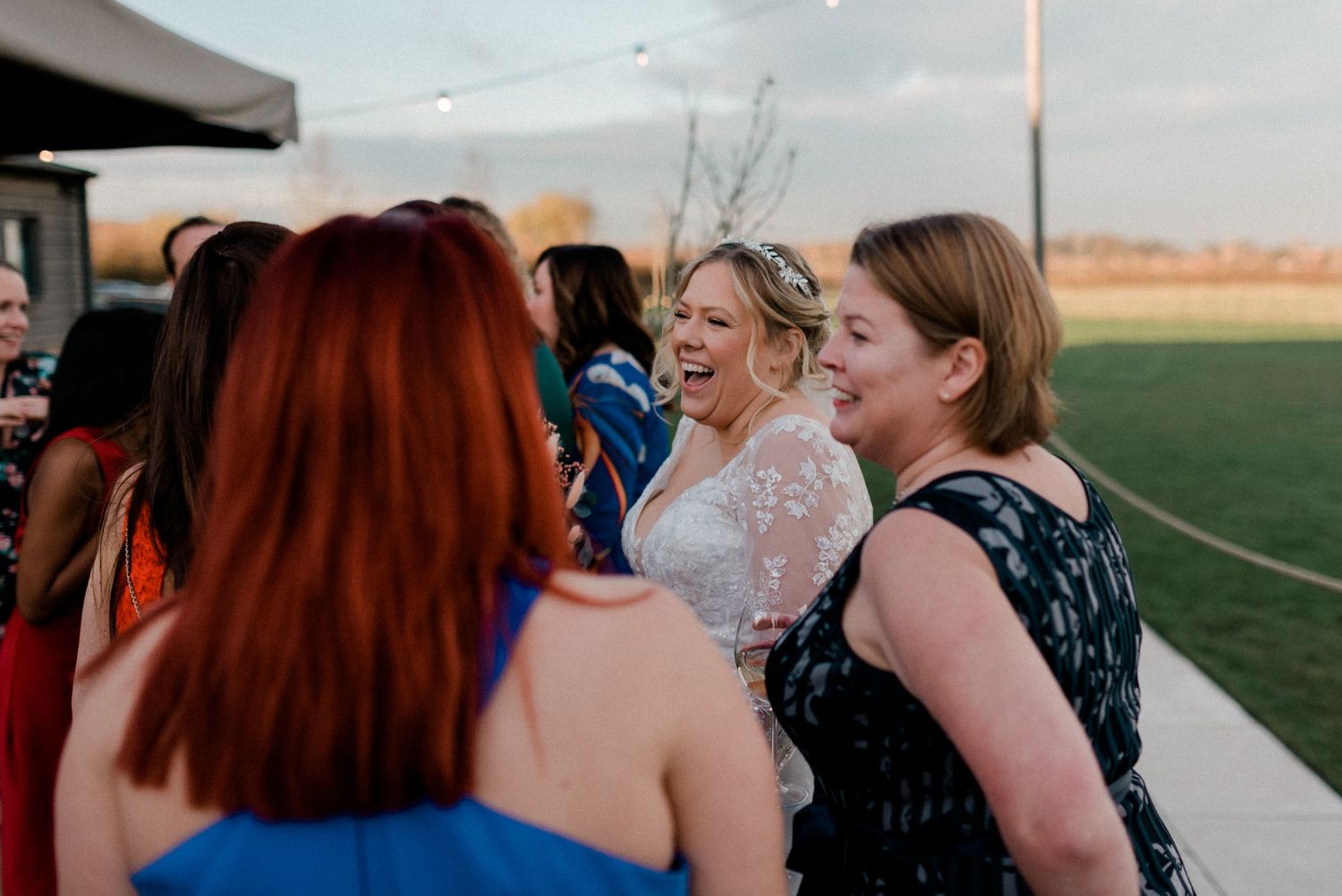 Wedding guests share laughs and conversations during an outdoor reception.