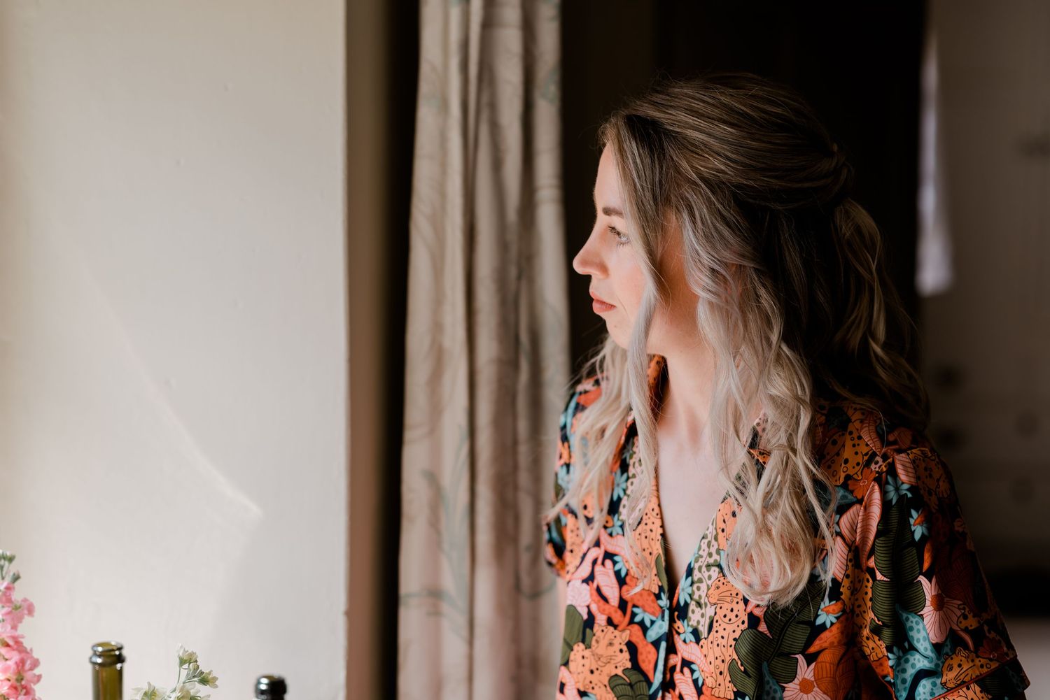 Couple laughing and sharing romantic moments in front of white curtained windows with floral accents.