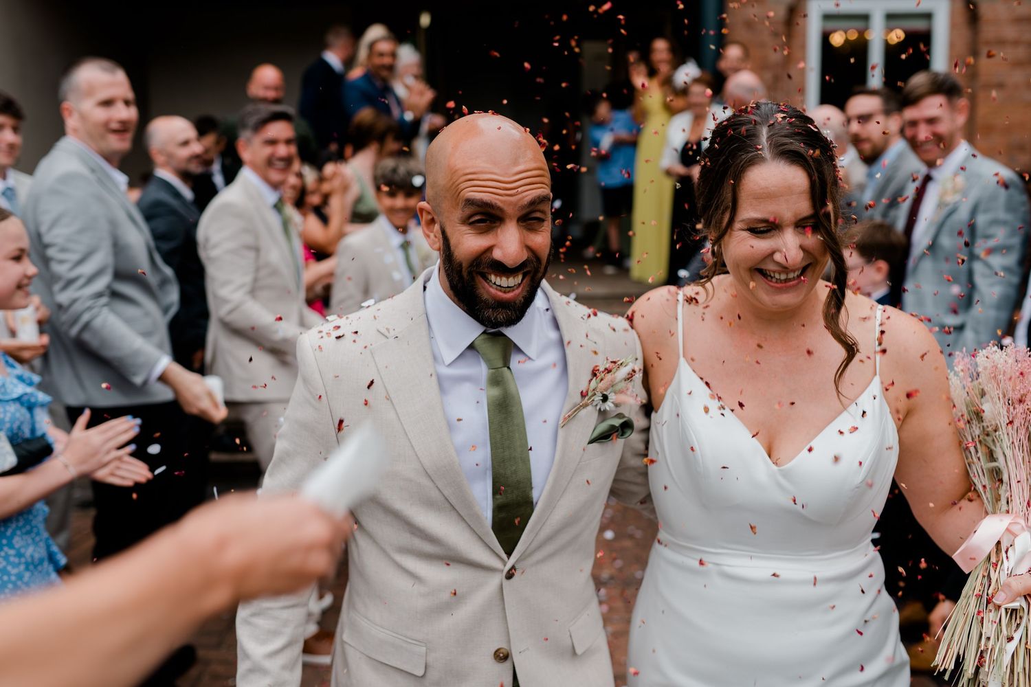 Wedding celebration scene with confetti falling as guests celebrate on a sunny day.