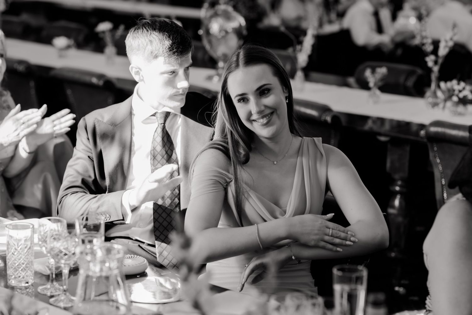 Wedding reception guests share laughter at dining tables.