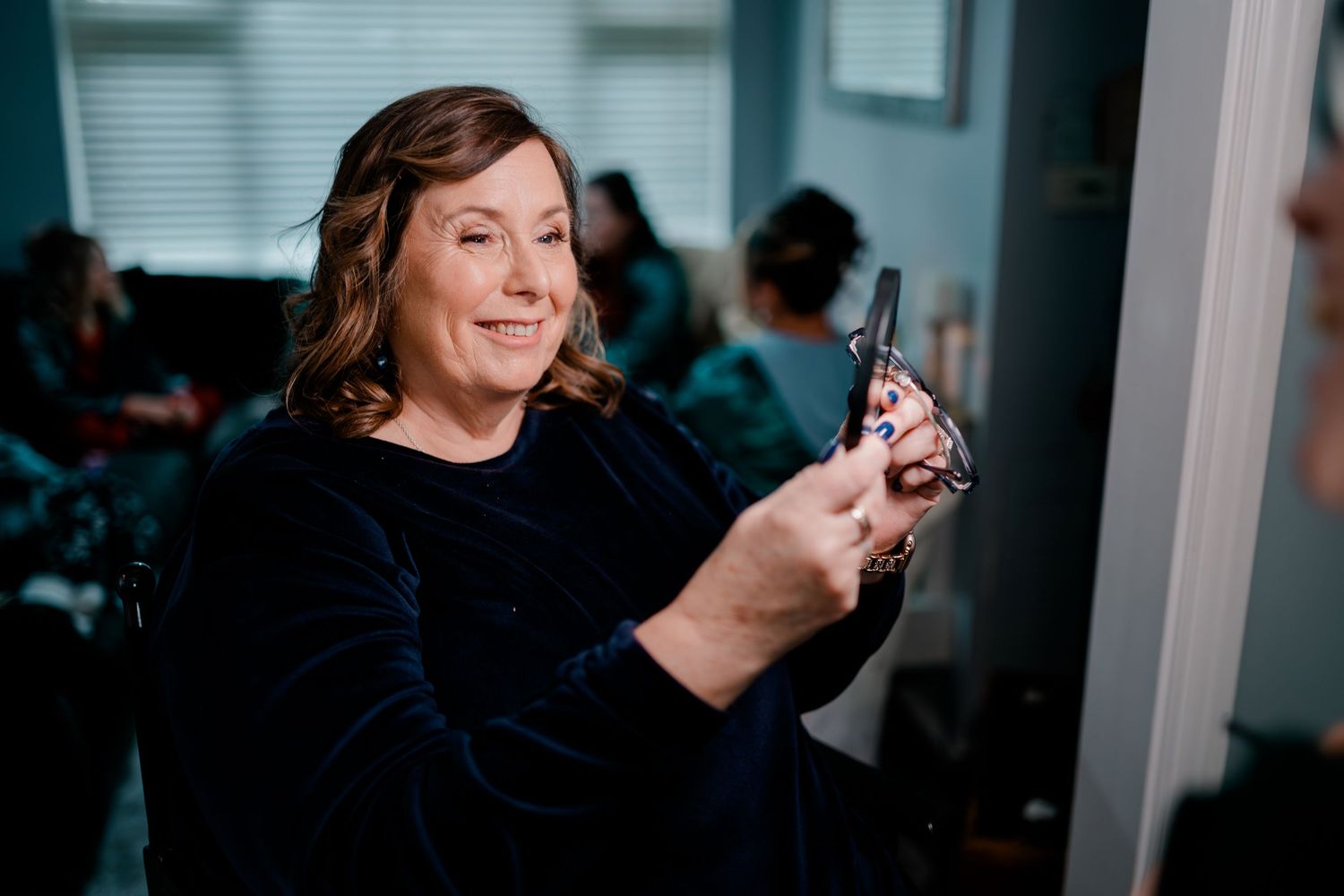 Woman smiling while holding hair curling iron at wedding prep salon.