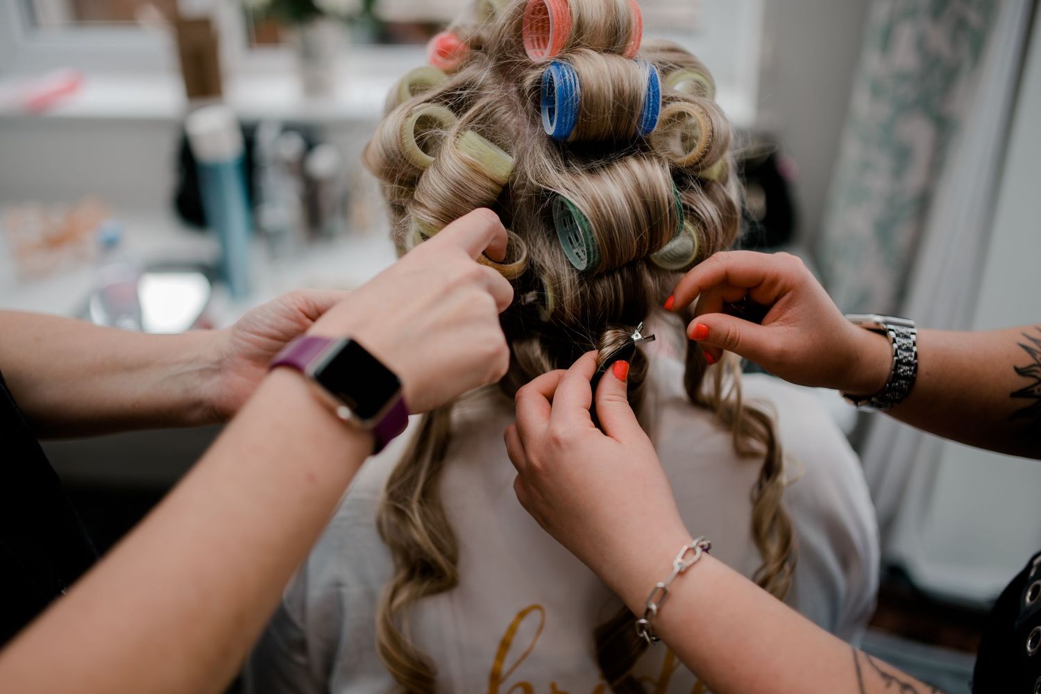 Hands styling hair with rollers during wedding preparation.