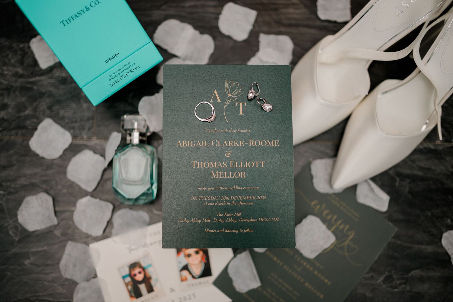 Elegant dark green wedding invitation with gold details, Tiffany perfume, and white heels.