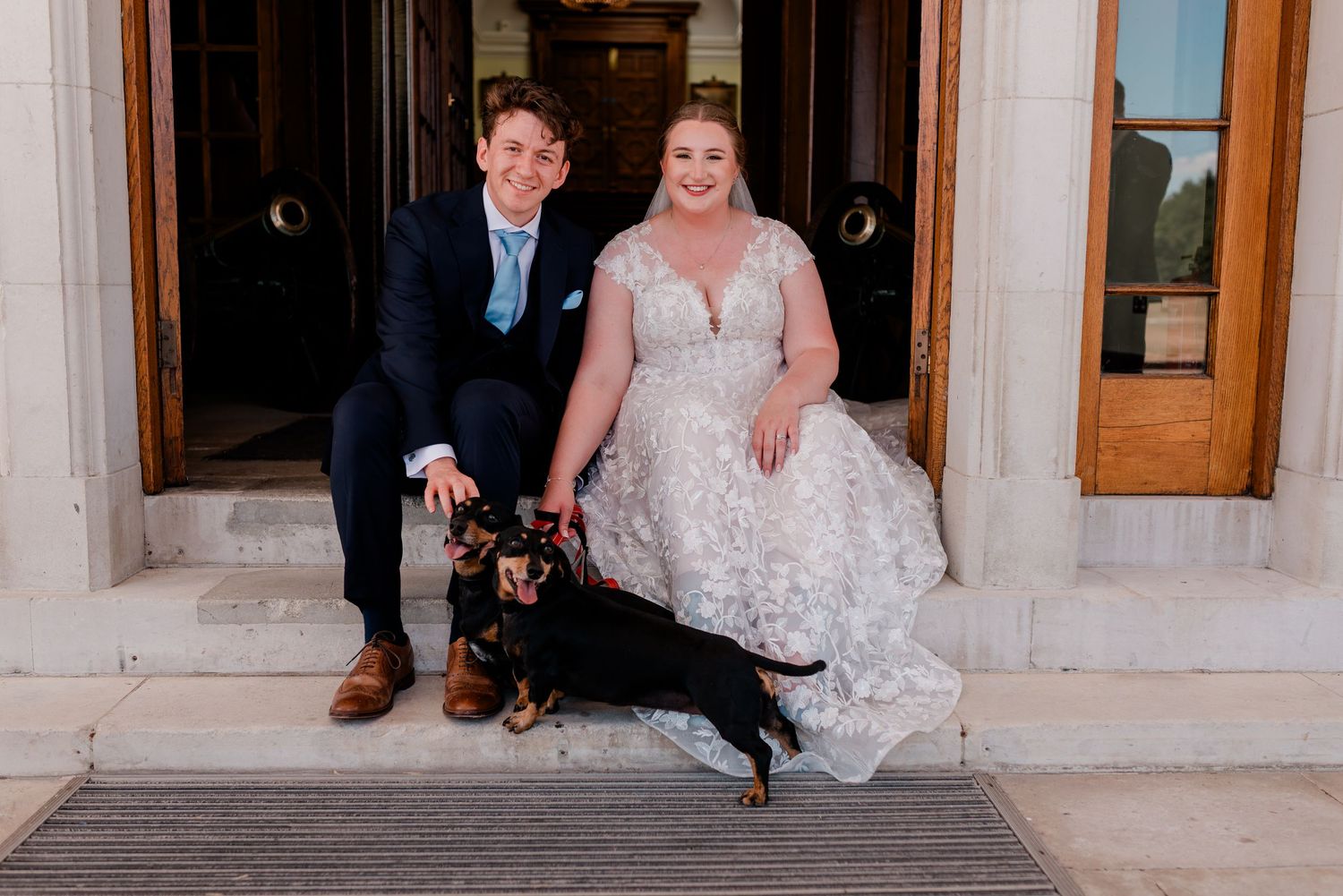 Wedding party poses together on ornate stone steps.