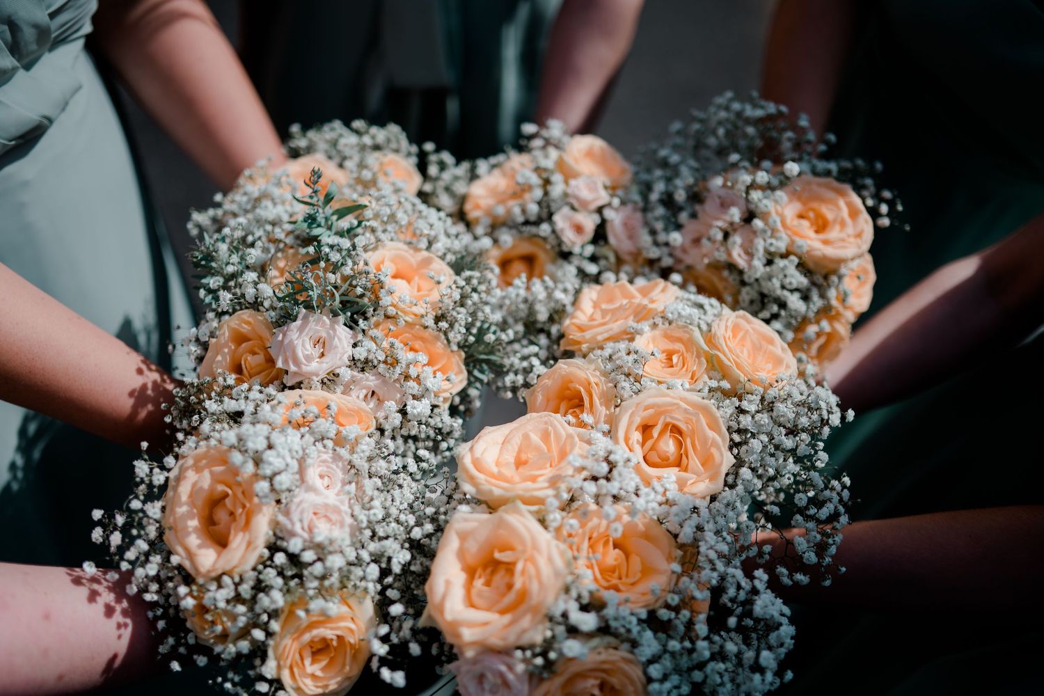 Bridesmaids holding a stunning collection of peach rose and baby's breath wedding bouquets.