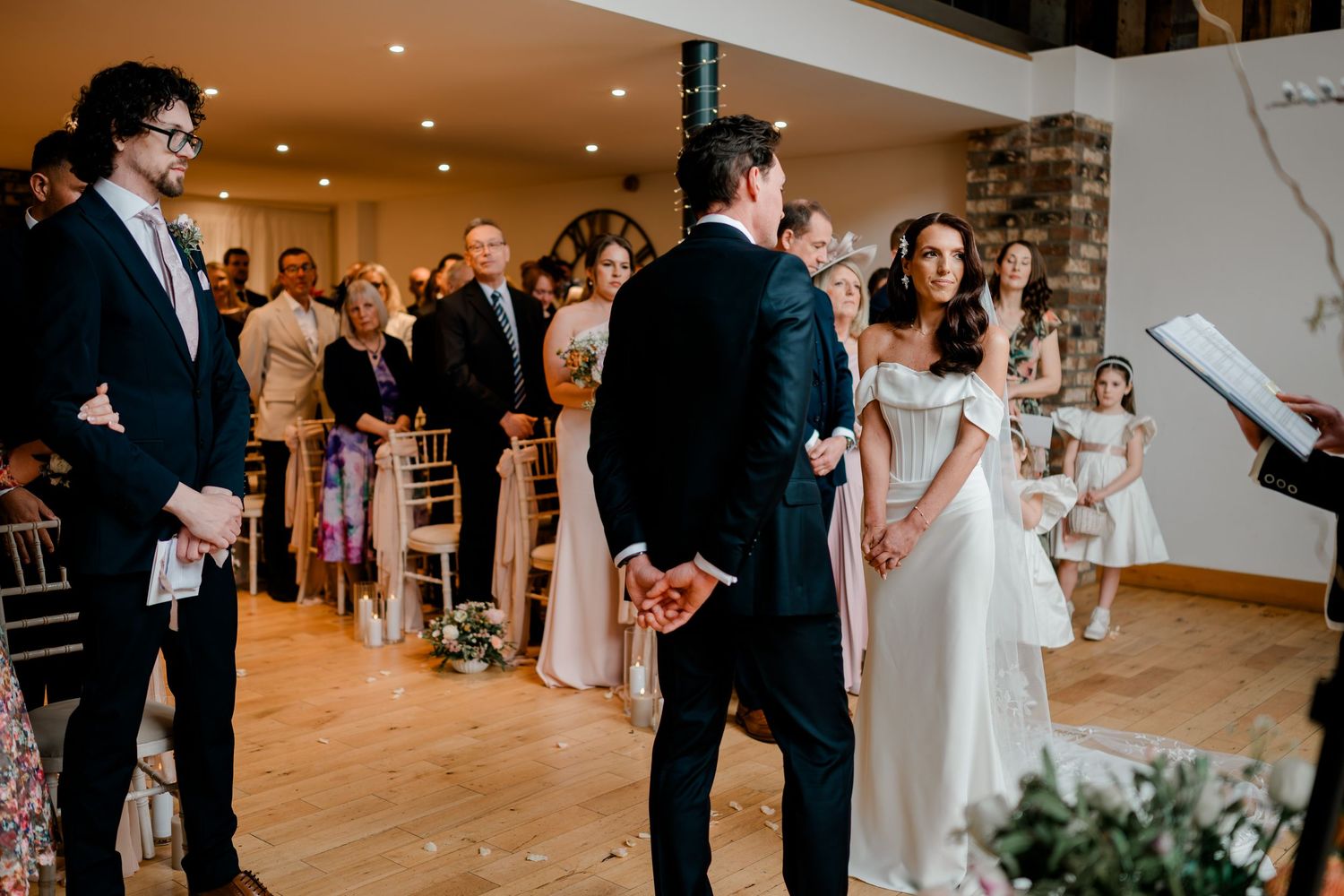 Bride and groom share a tender moment at the altar during their elegant indoor wedding ceremony.