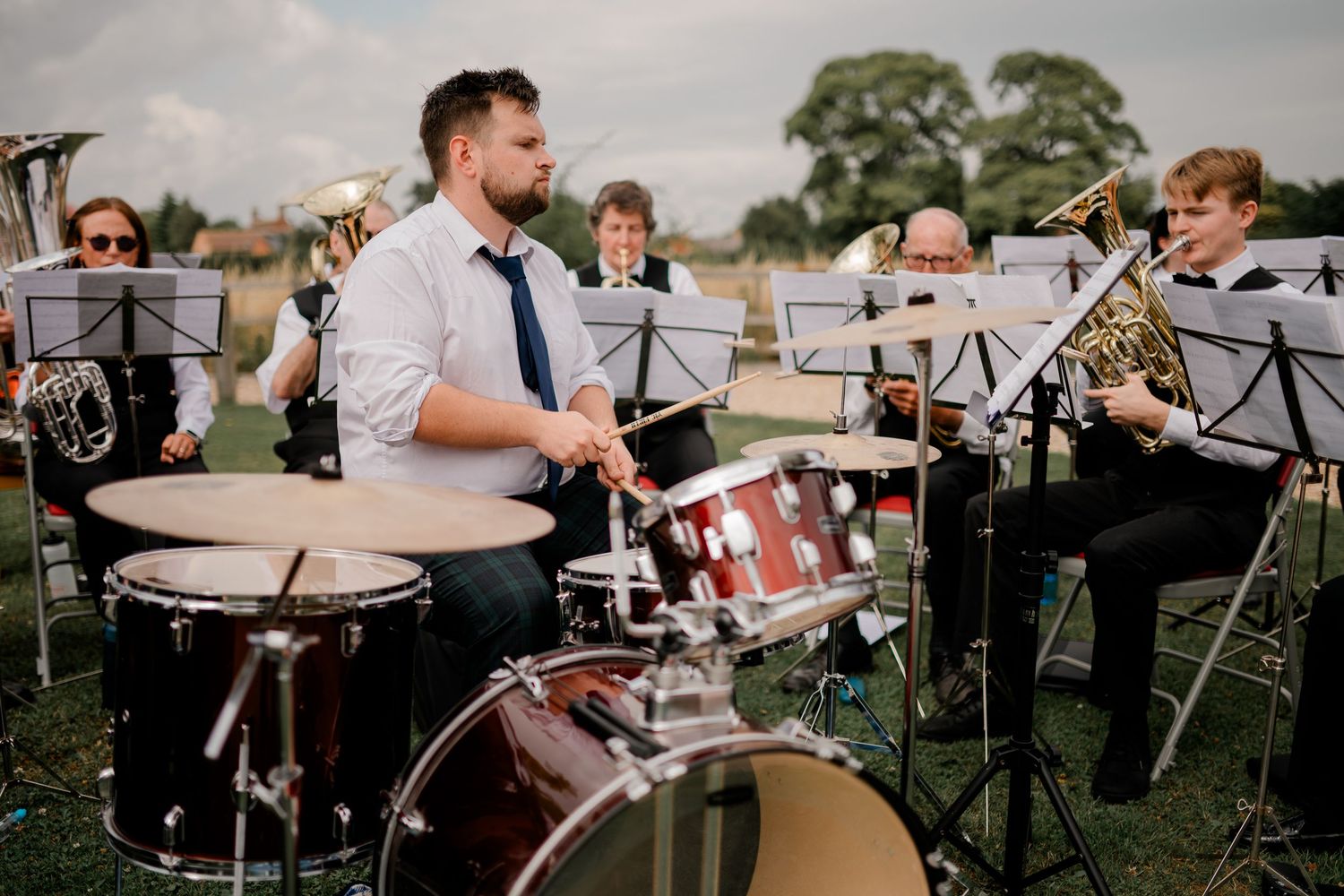 Live band performs with drums and instruments at an outdoor wedding reception.