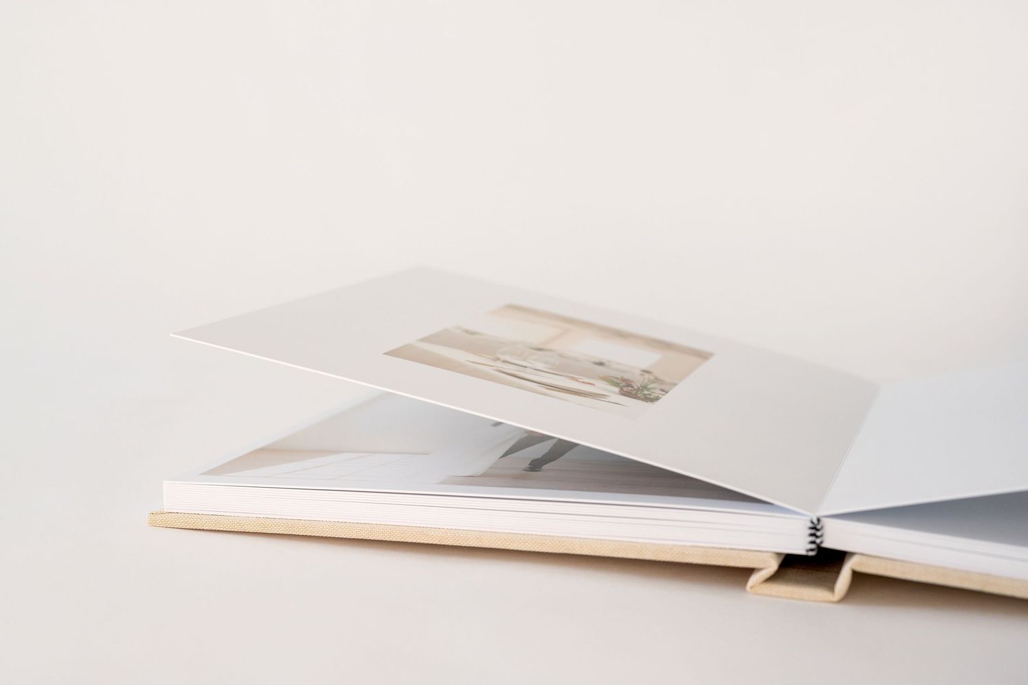 Open photo album with printed landscape photograph on white pages, displayed on a light background.