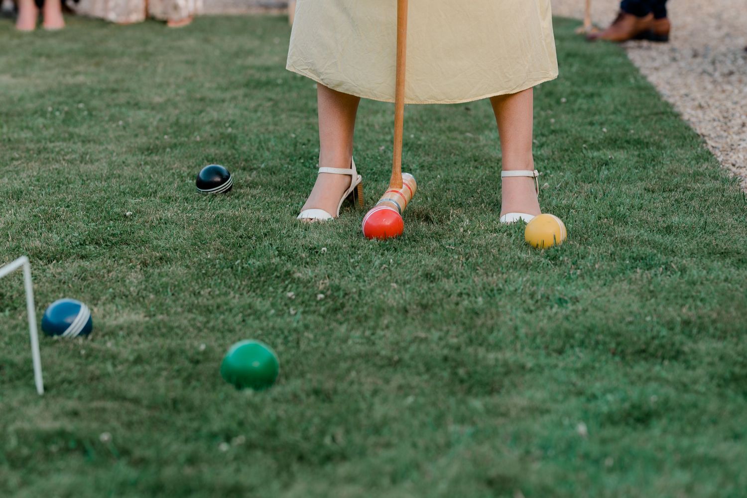 Croquet mallets and colorful balls arranged on green lawn for outdoor wedding games.