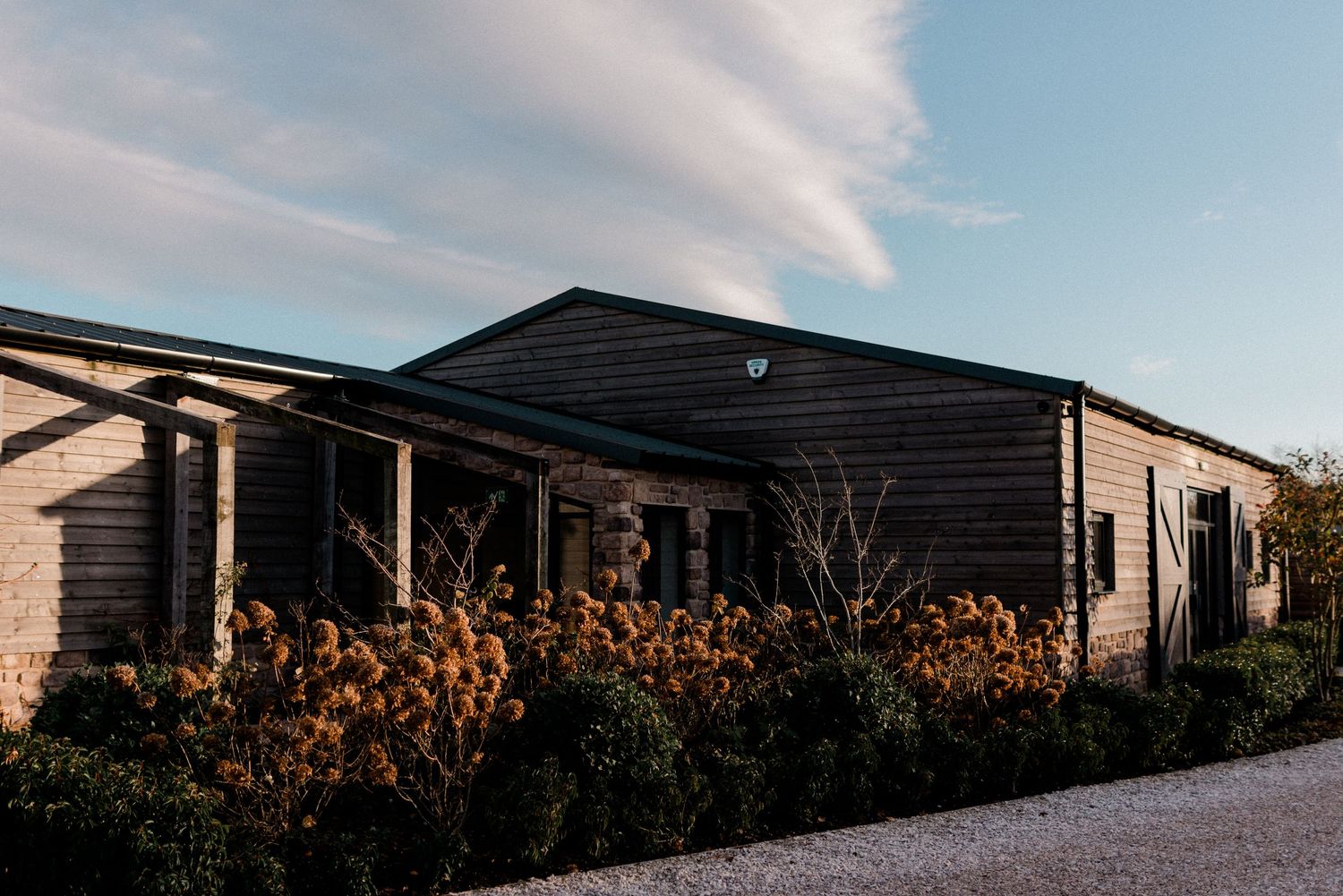 Stretton Manor Barn venue with rustic landscaping against blue sky.