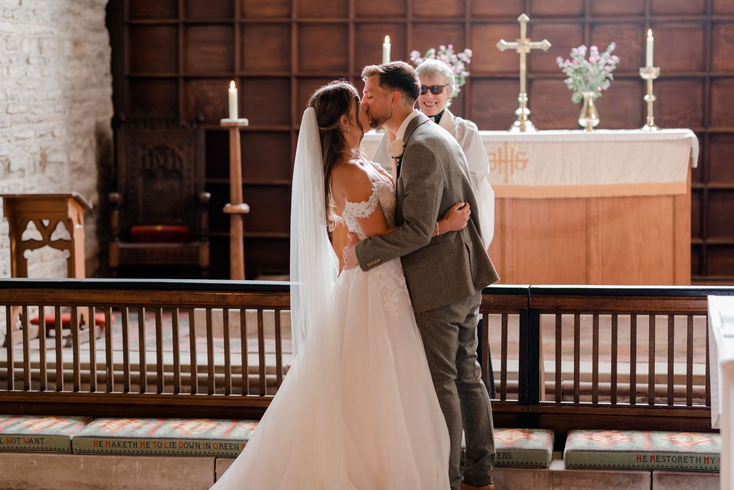 A wedding ceremony takes place in a traditional church sanctuary with exposed stone walls and wooden details.