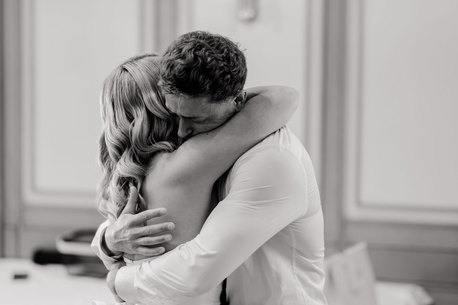 Tender black and white photo of a bride and groom sharing a heartfelt embrace on their wedding day.