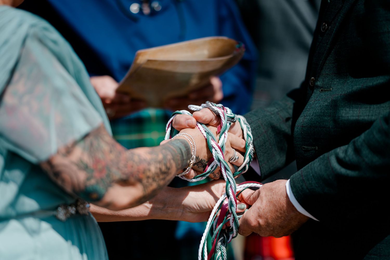 Couple's hands bound together with colorful ribbons in a handfasting wedding ceremony.