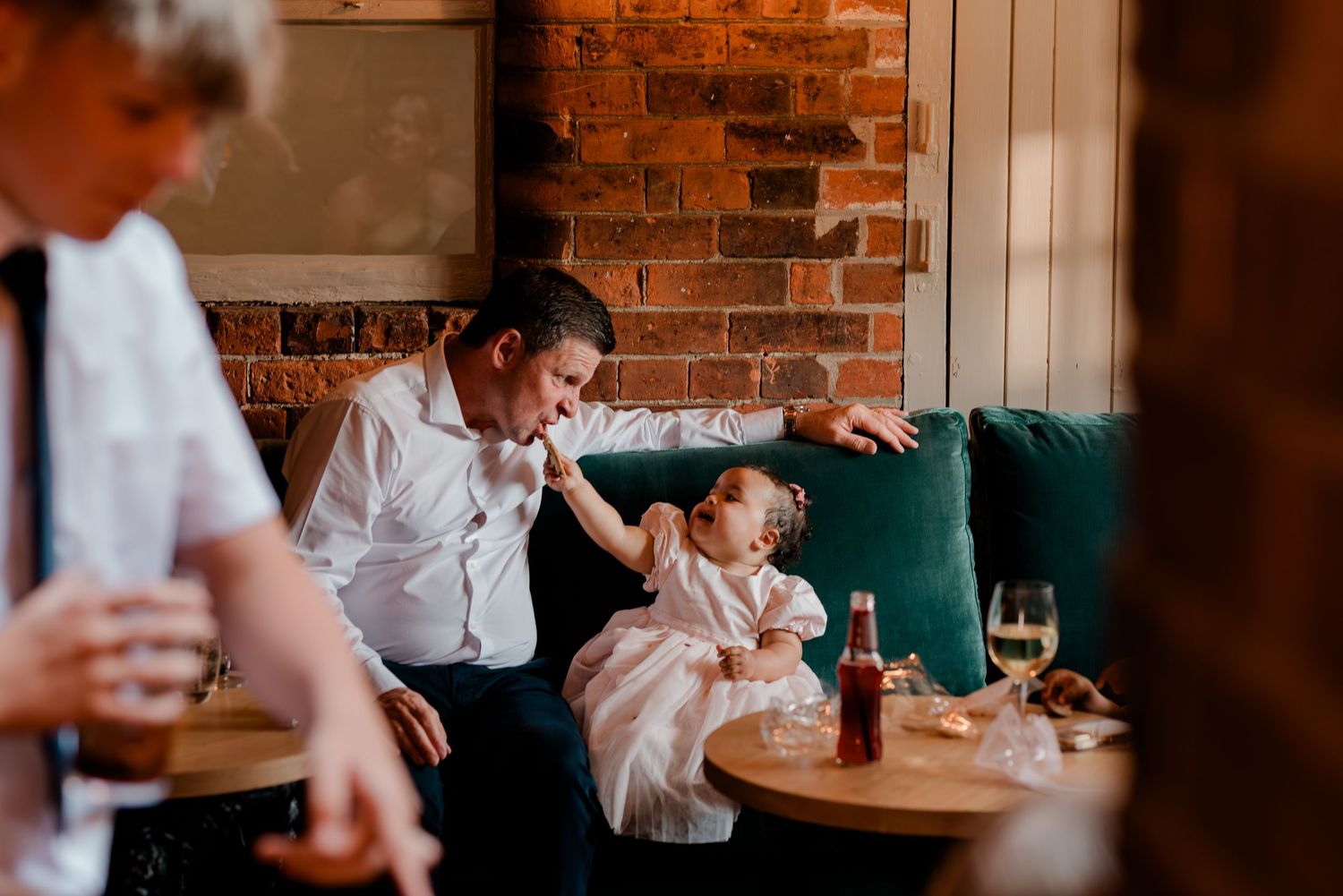 Wedding guests enjoying drinks and conversation at a rustic brick-walled venue.