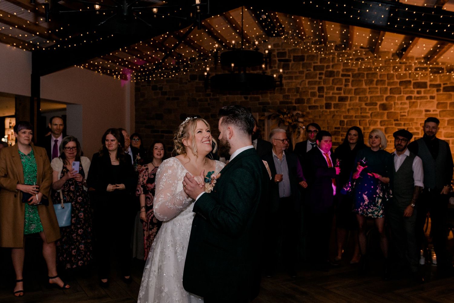 Couple shares their first dance under romantic string lights at their wedding reception.