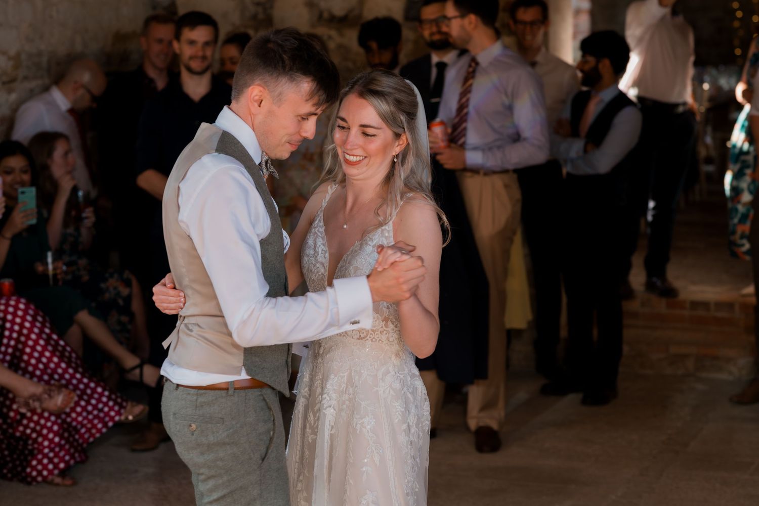 Dancing couples enjoying themselves at an indoor wedding reception with string lights.