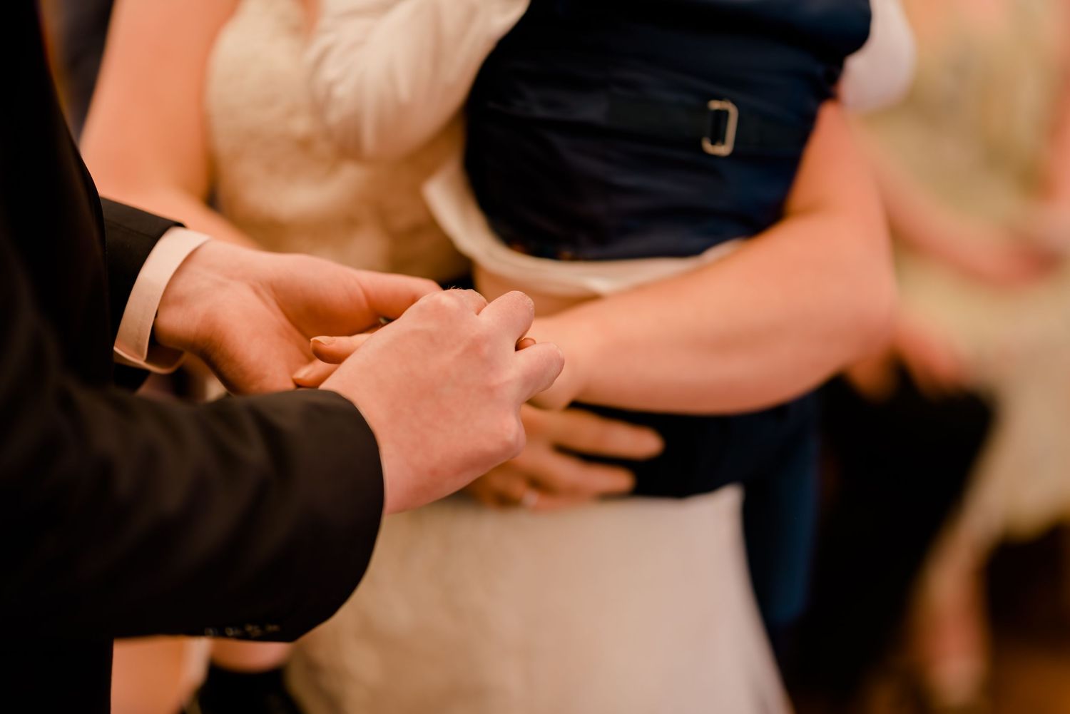 Close-up of hands during an intimate wedding ceremony moment.