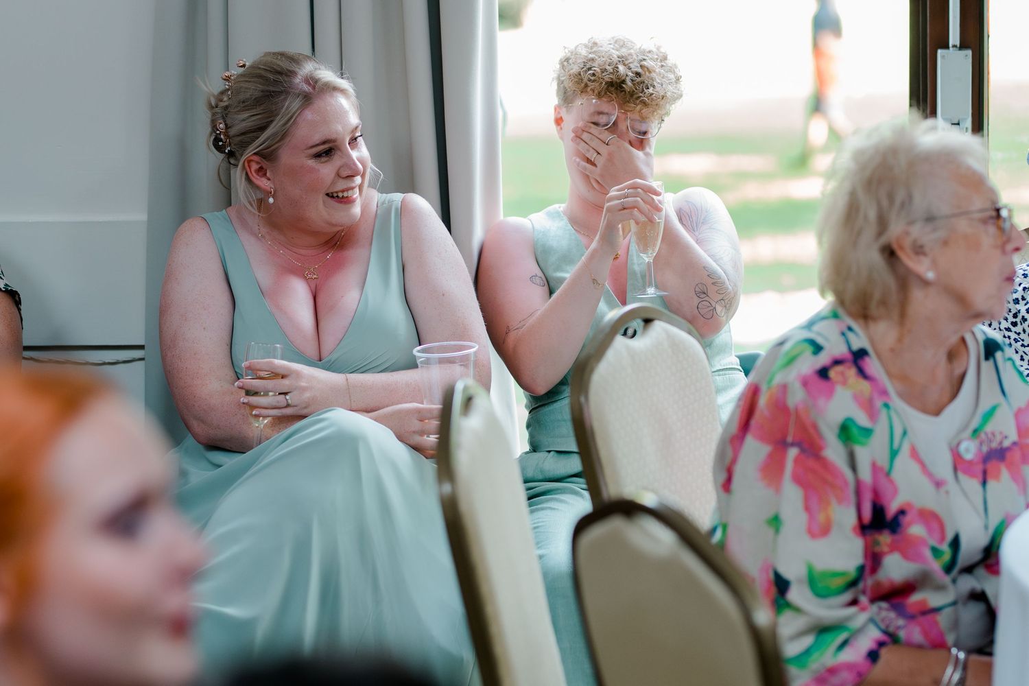 Wedding guests in pastel dresses share emotional reactions during a reception celebration.