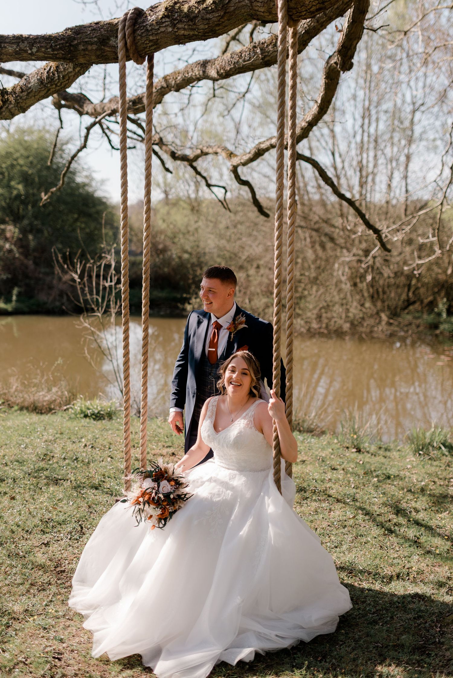 A serene outdoor wedding scene with a rustic tree swing by a tranquil pond backdrop.