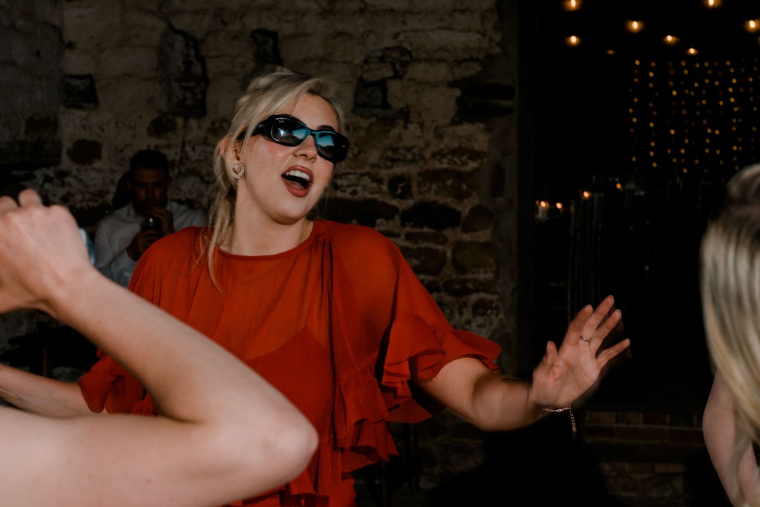 People dancing enthusiastically at a dimly lit wedding reception party.