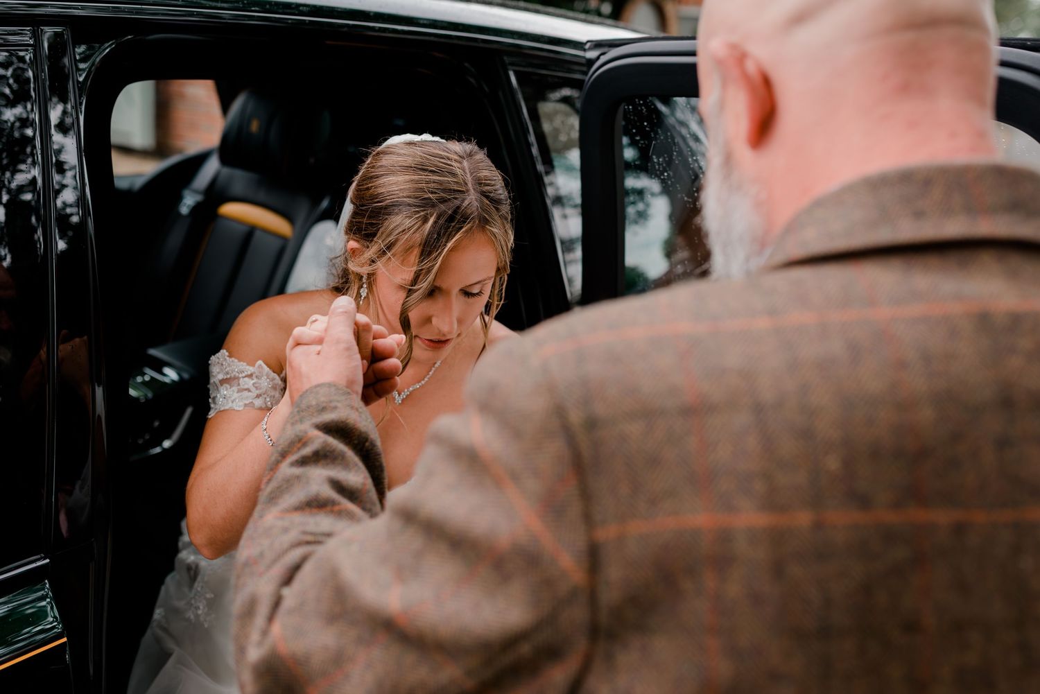 A couple embraces in a romantic moment inside a dimly lit car interior.