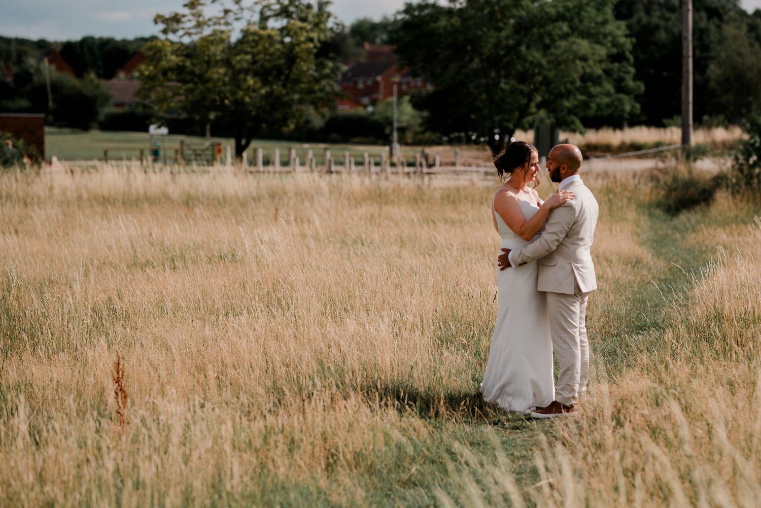Couple embracing in a golden field during sunset at their wedding.