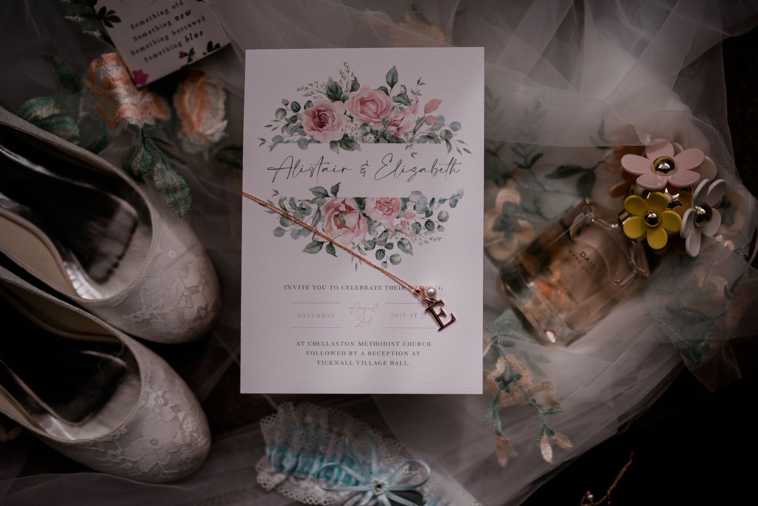 Wedding invitation with floral design surrounded by vintage accessories and tulle.
