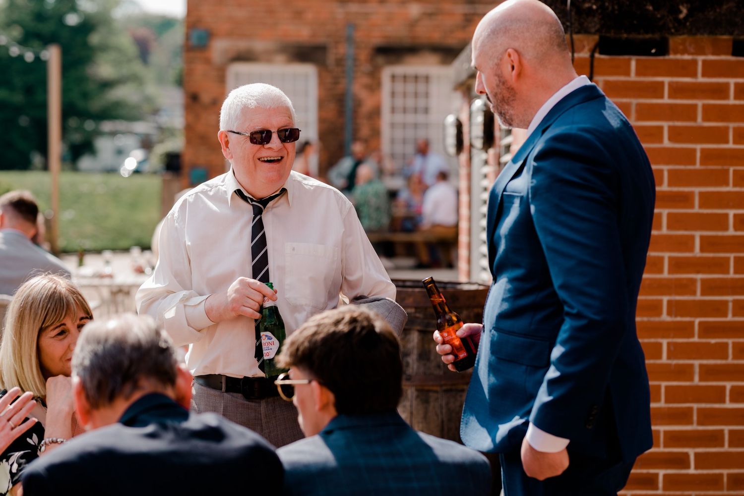Wedding guests enjoying drinks and conversation at an outdoor brick venue.