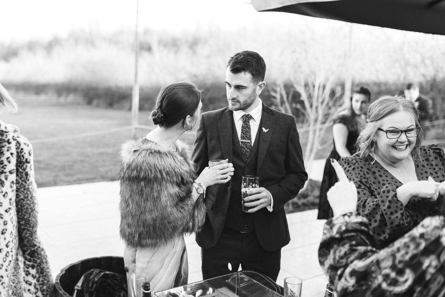 Black and white photo of wedding guests mingling at an outdoor reception.