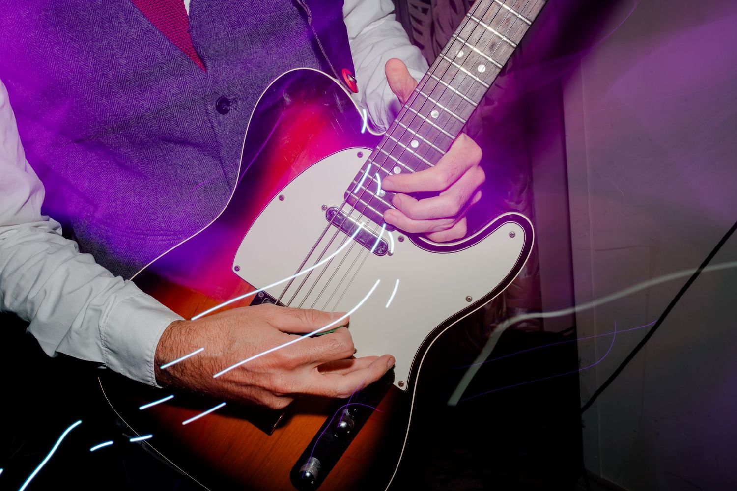 Close-up shots of hands playing electric guitar with purple and red stage lighting.