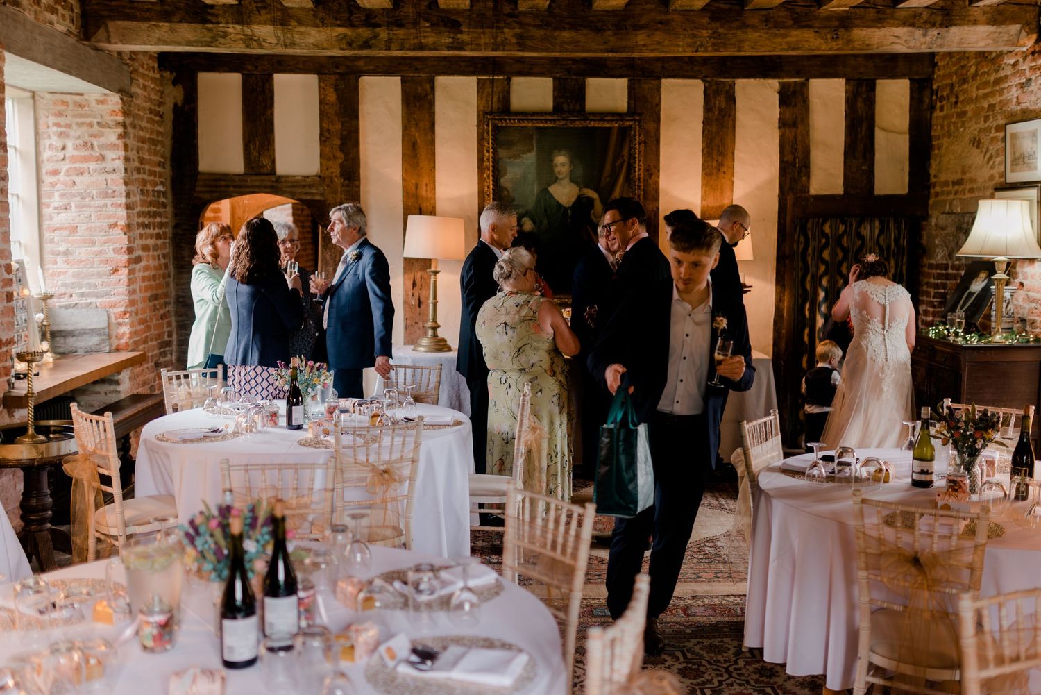 Elegant wedding reception setup with white linens and rustic wooden beams in historic venue.