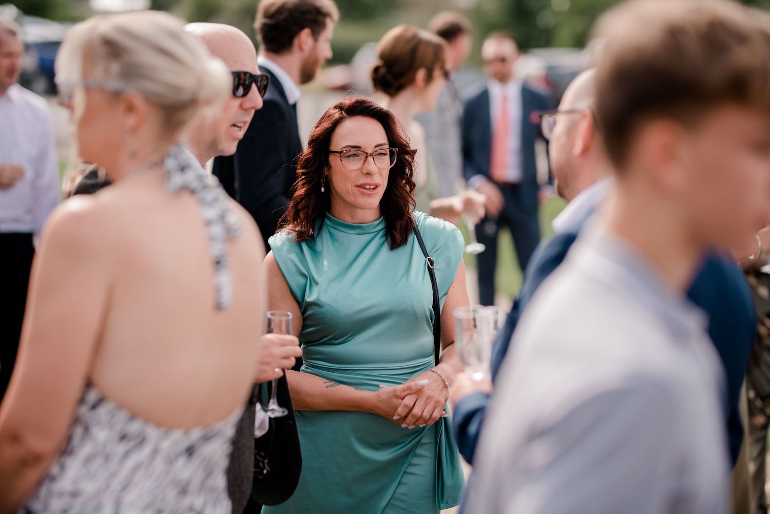 Wedding guests chat and enjoy drinks at an outdoor summer celebration.