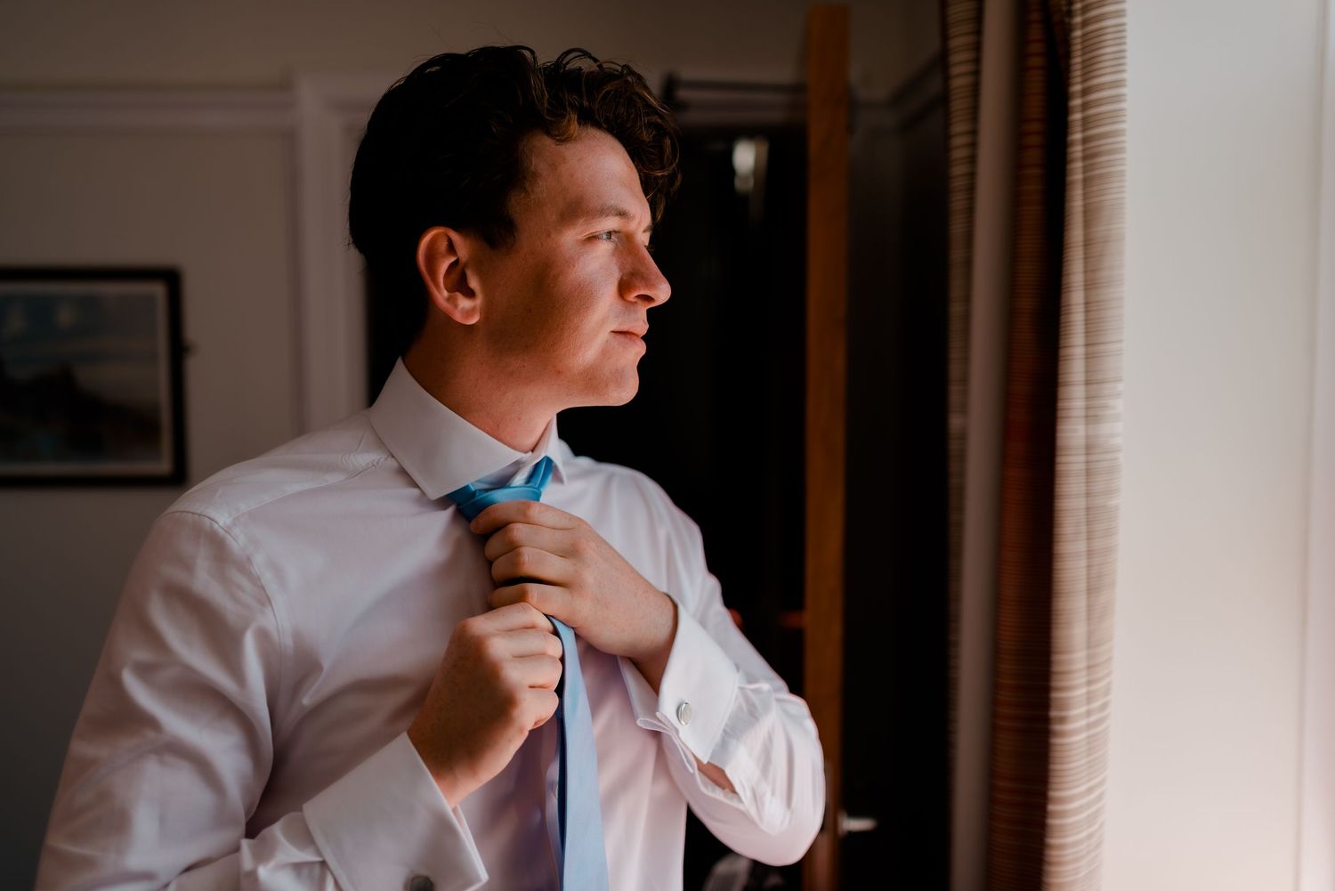 A series of atmospheric portrait shots capture someone in a white shirt looking pensively by a window.