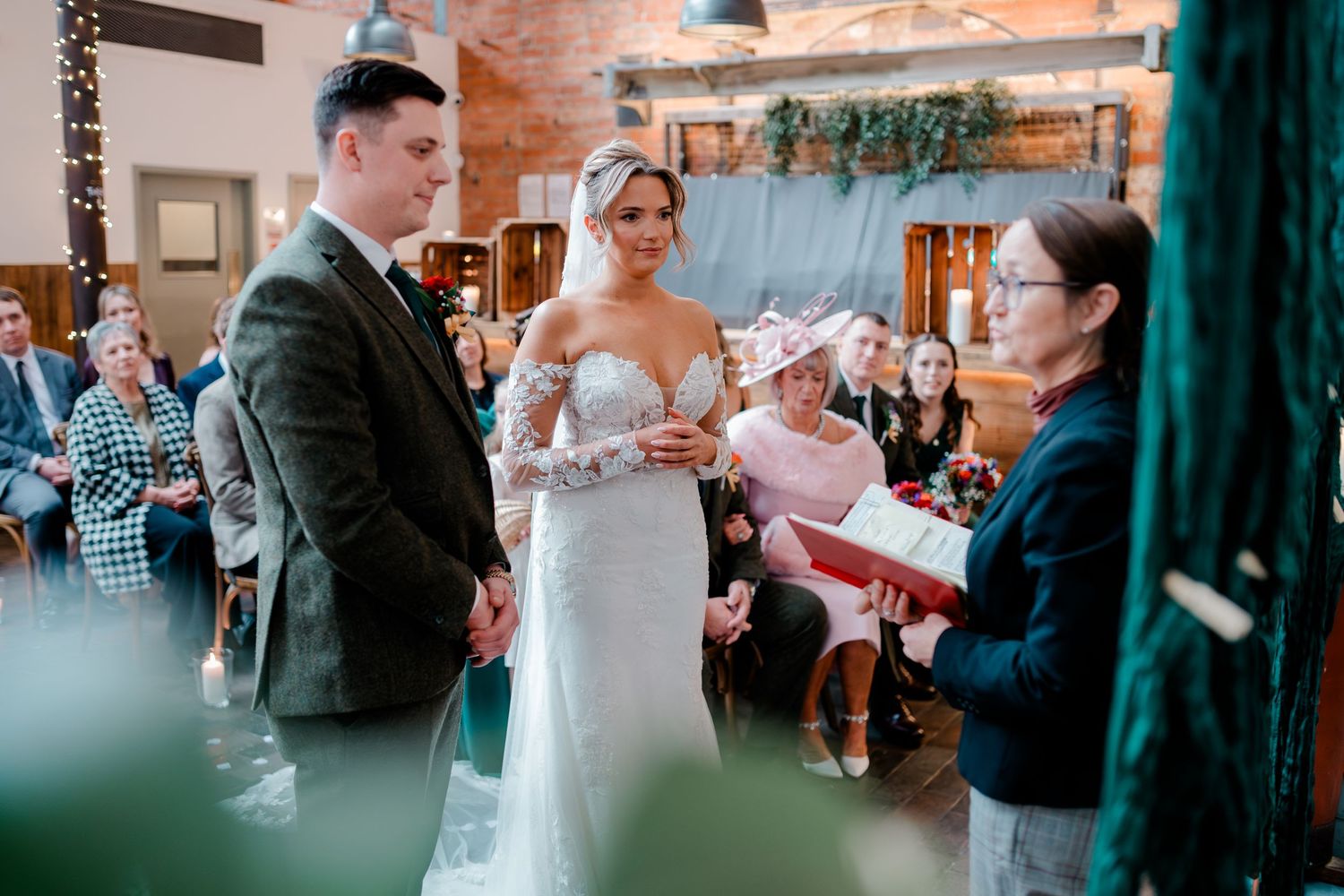 Bride and groom exchange vows before officiant in romantic candlelit wedding ceremony venue.