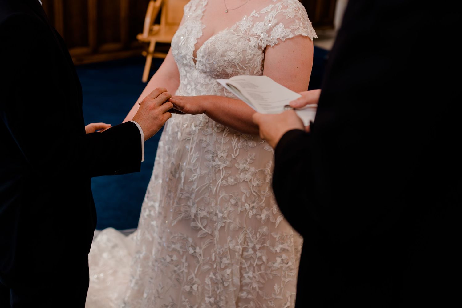 A wedding guest in a formal pink gown stands at an outdoor wedding venue during golden hour.