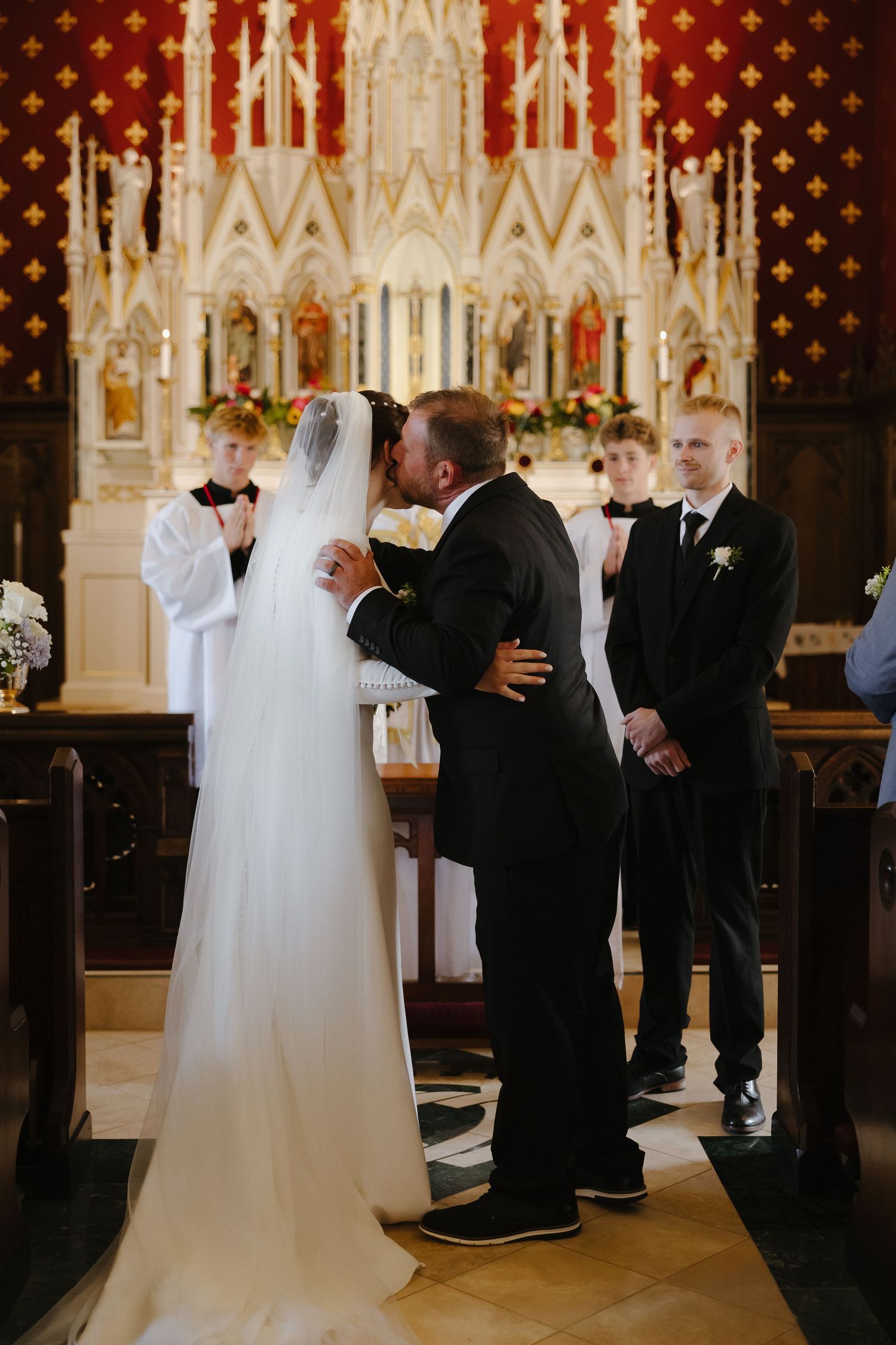 Wedding ceremony taking place in a cathedral with beautiful stained glass and architectural details.