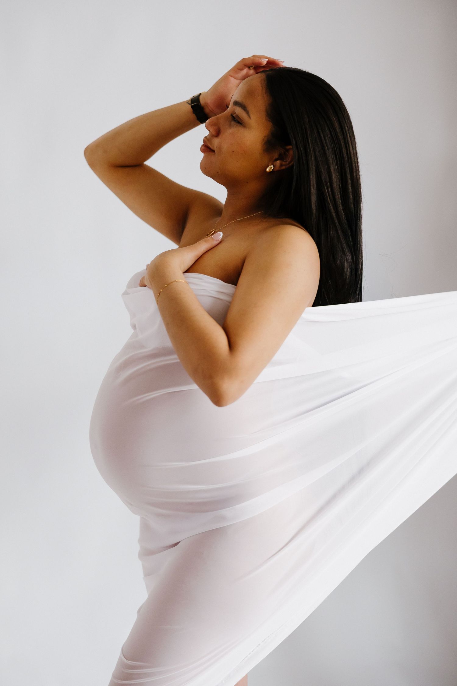 Artistic maternity photos with flowing white fabric creating elegant movement and form.