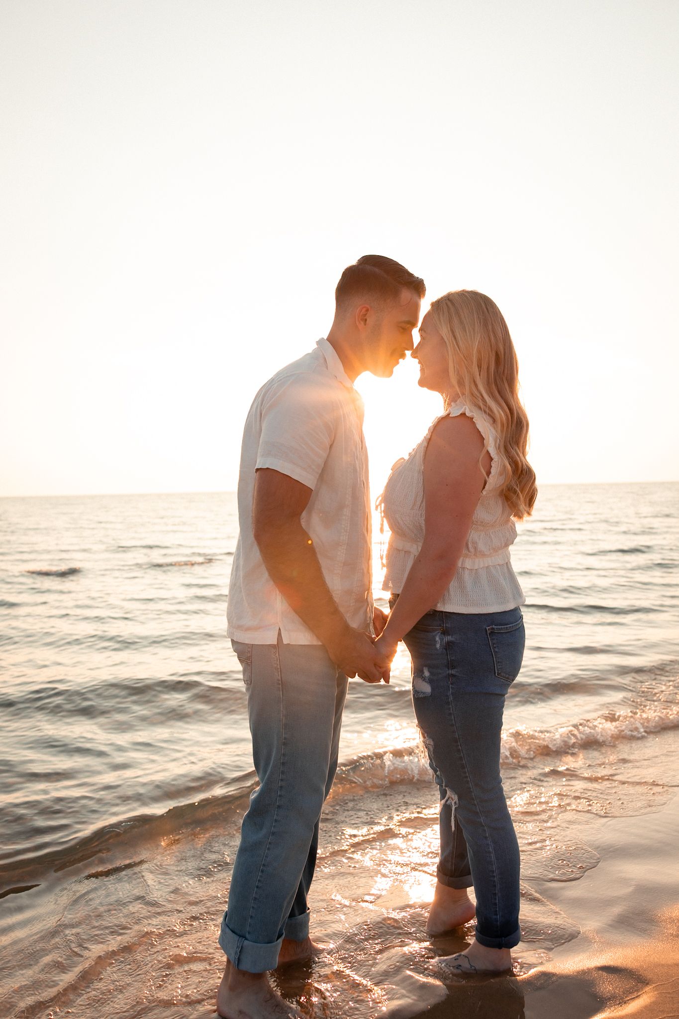 Romantic sunset beach engagement photos with couple silhouetted against ocean.