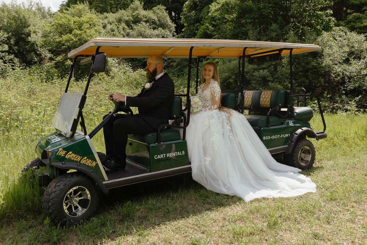 Bride and groom riding a green golf cart through lush greenery on their wedding day.