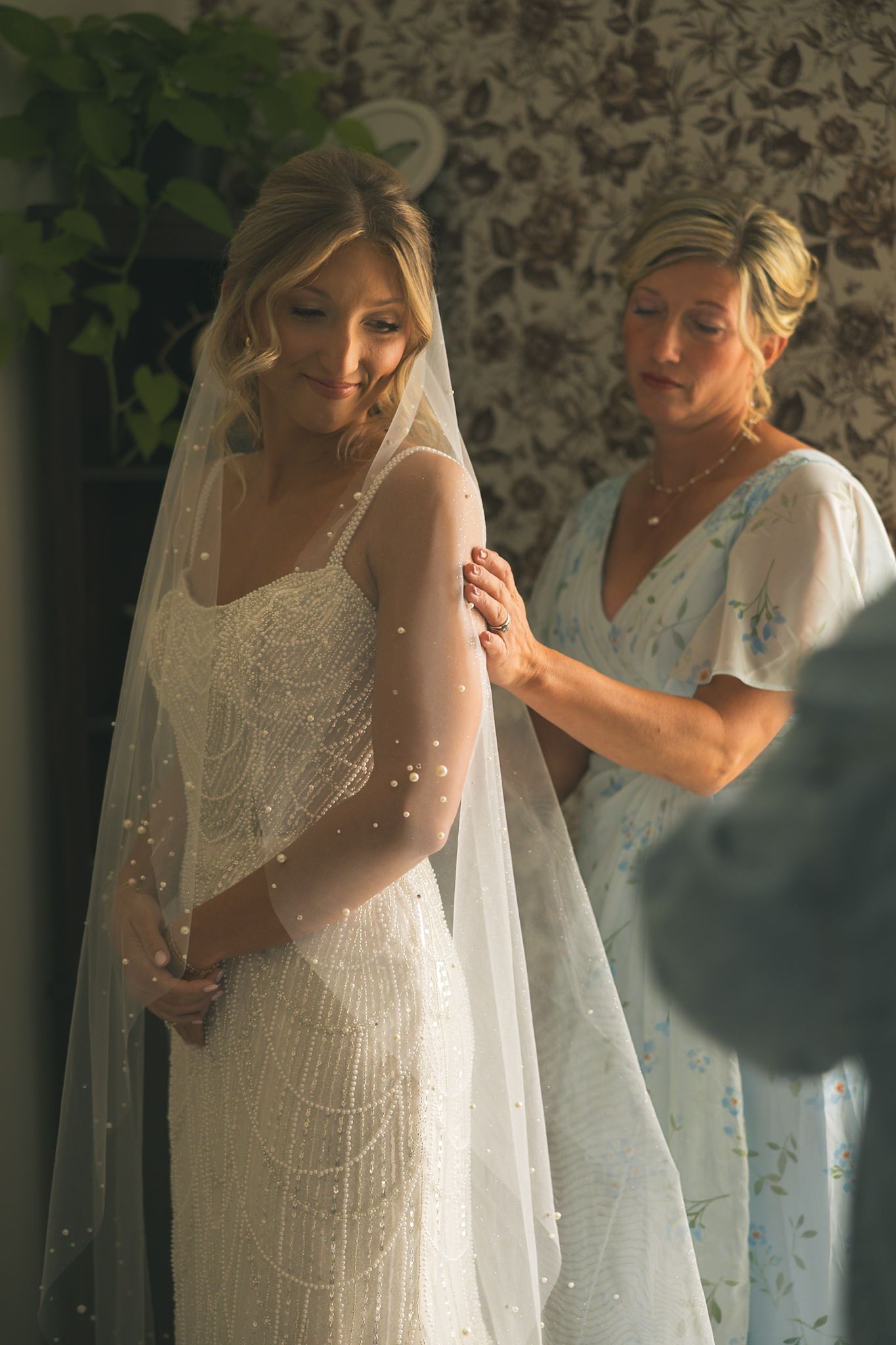 A series of photos showing a wedding dress being fitted and adjusted with delicate beading and veil details.