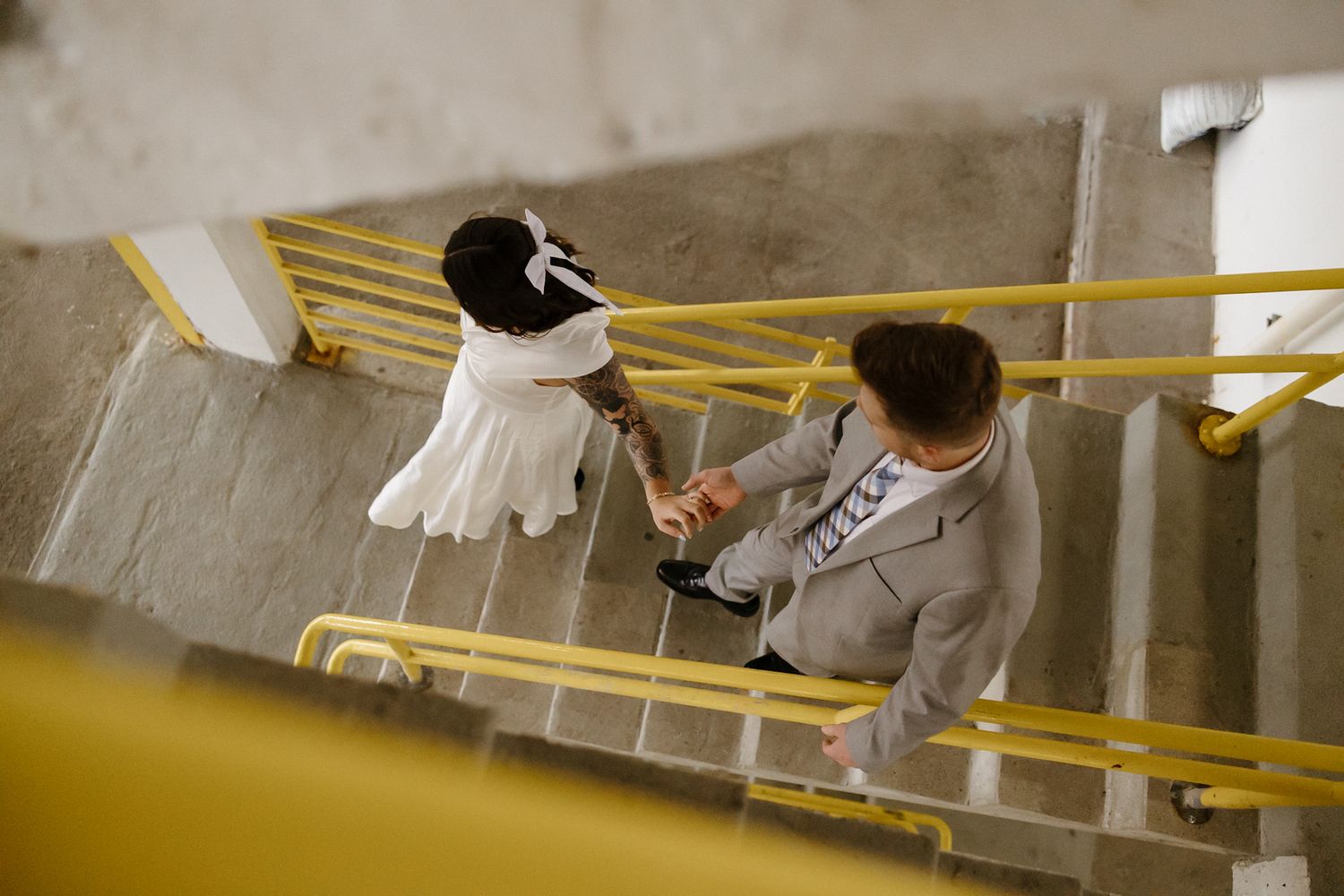 Couple dancing under yellow industrial lighting in concrete hallway.