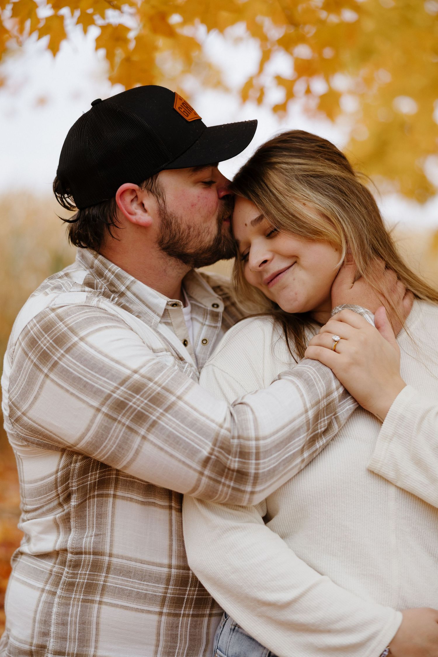 A romantic autumn engagement photoshoot with golden fall foliage in the background.