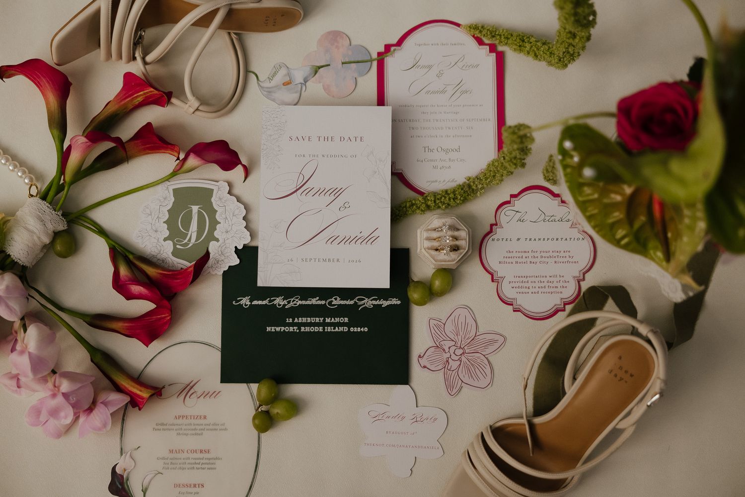 Wedding invitation suite with red calla lilies and pink floral accents arranged on a light background.