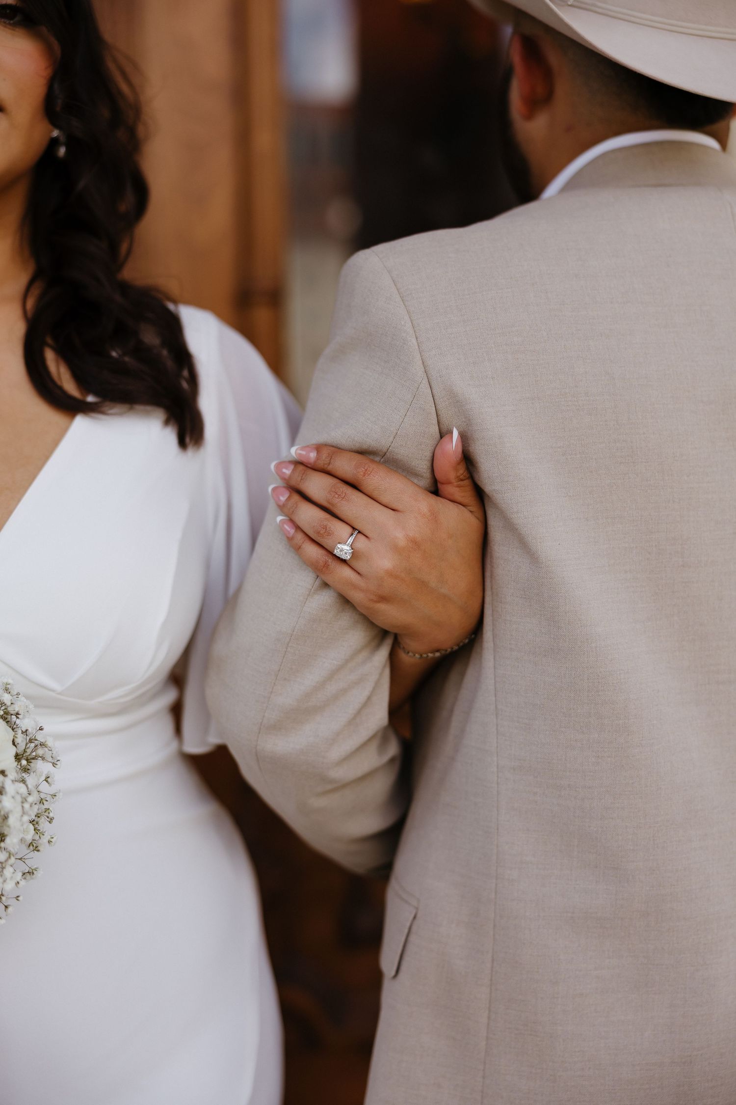 Close-up of couple embracing in white formal attire.