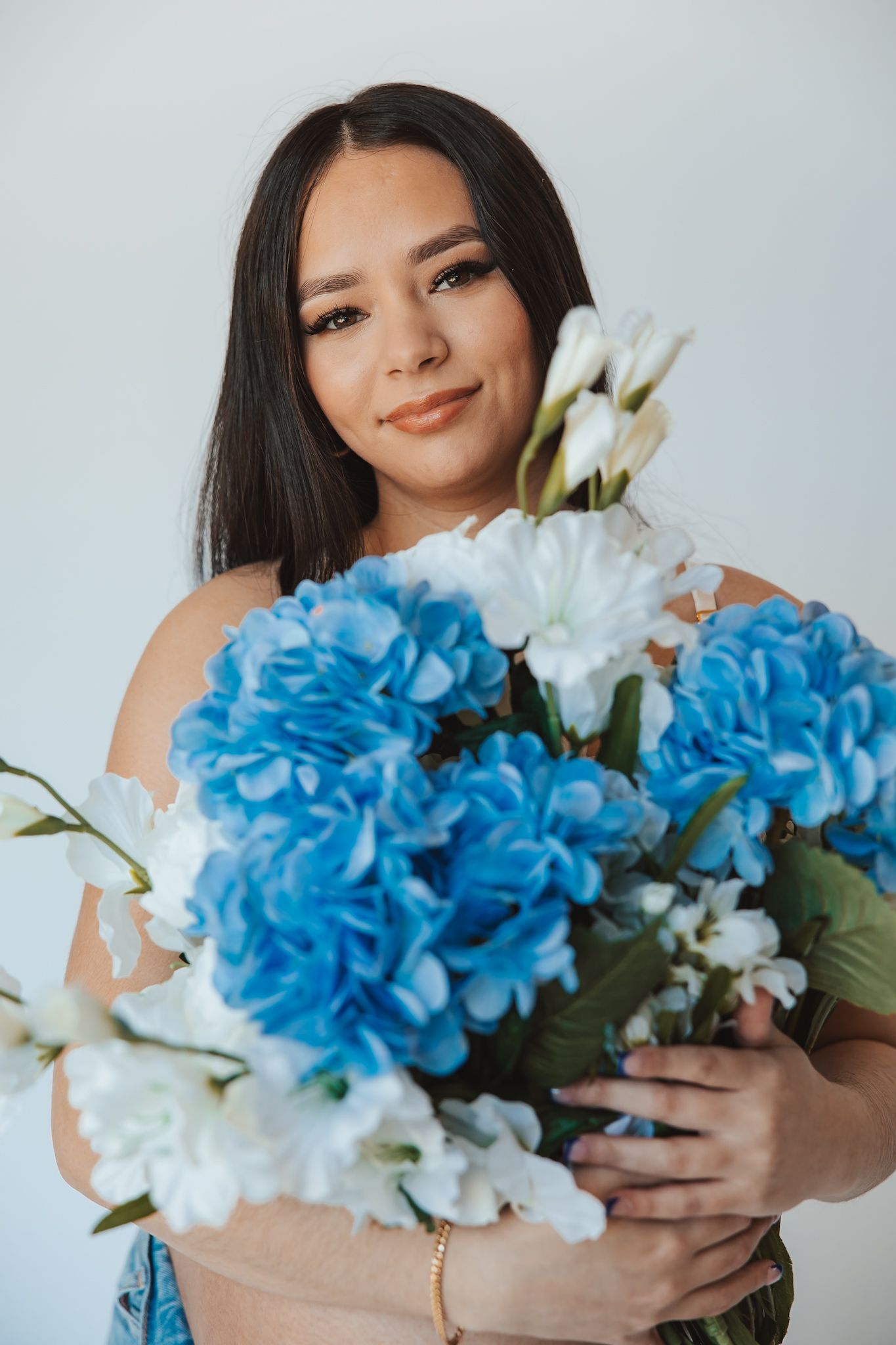 Close-up shots of woman holding bouquet with blue hydrangeas and white flowers.