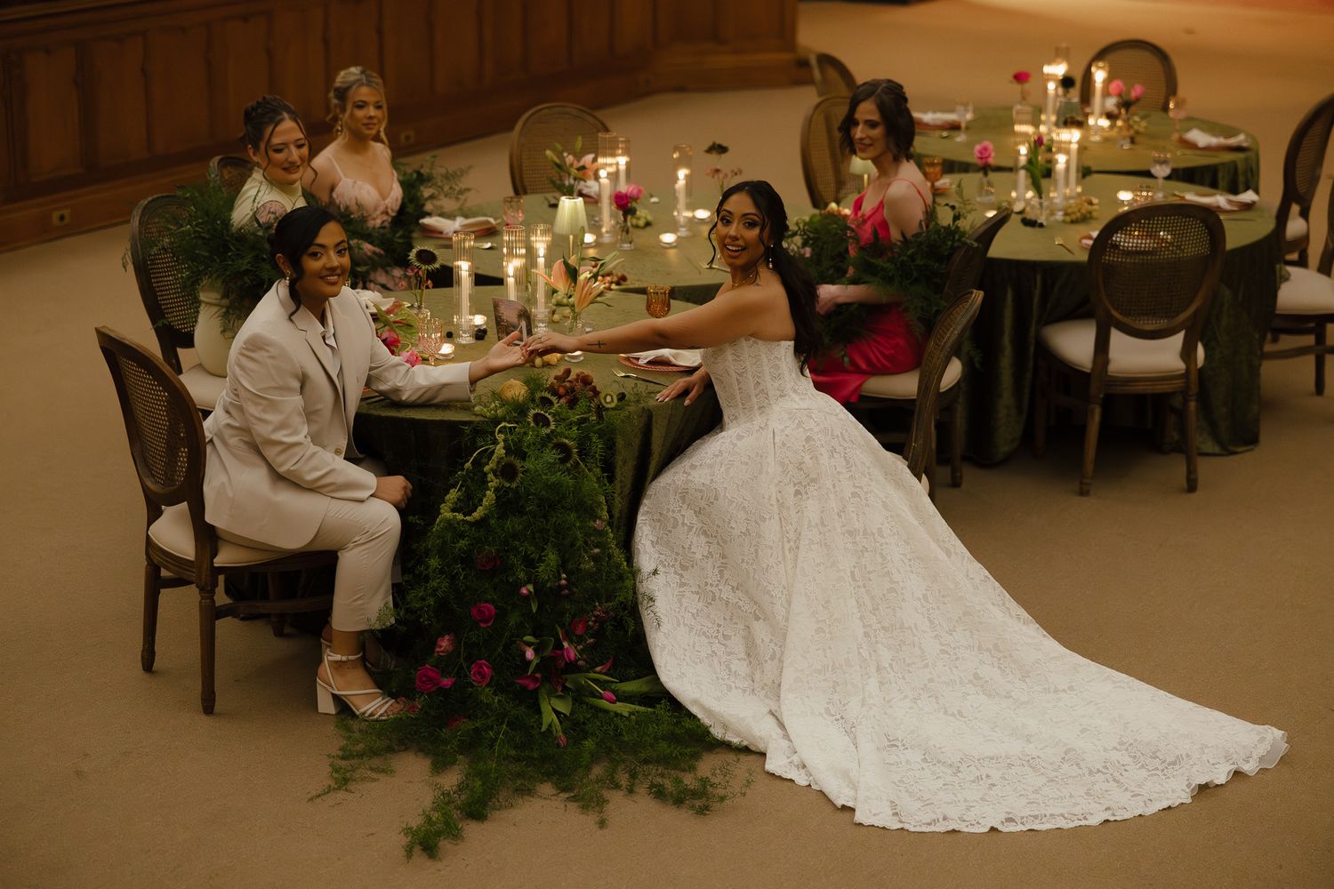 A wedding reception scene with elegant table settings and a flowing white bridal gown in a banquet hall at sunset.