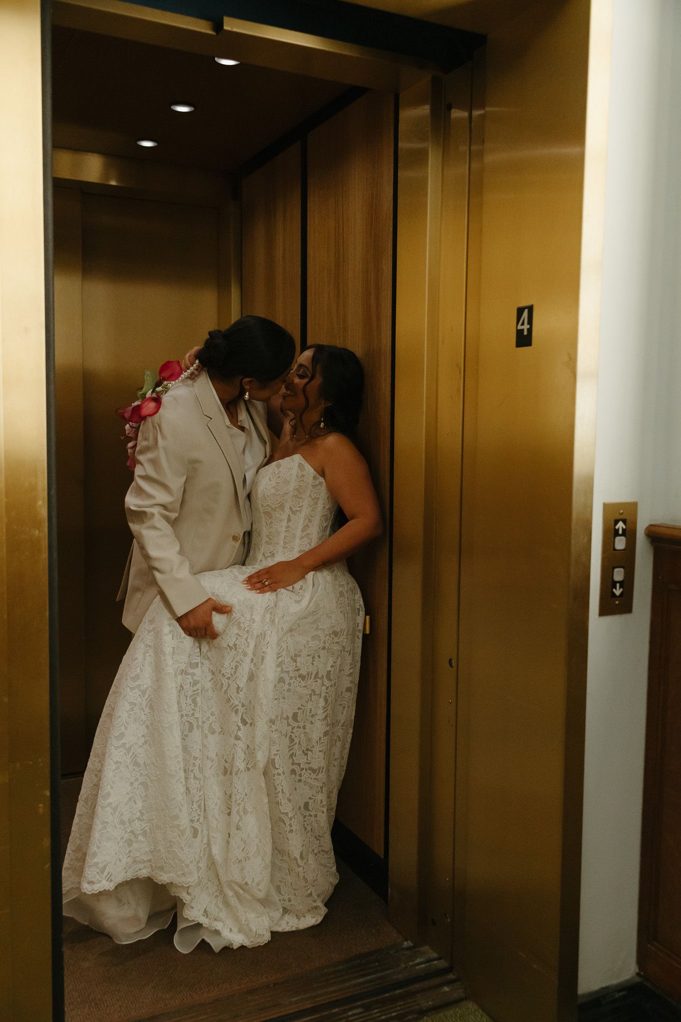 A couple in wedding attire share a romantic dance moment in an elevator hallway.