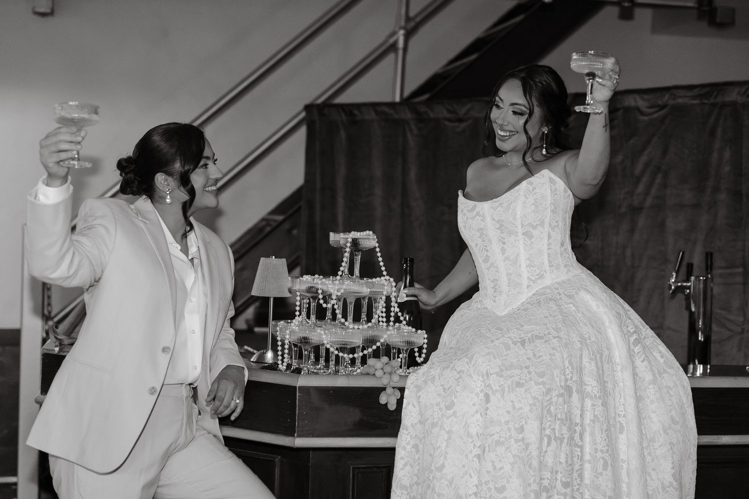 A couple in formal attire dances together at a wedding reception, with the bride wearing a white ballgown.