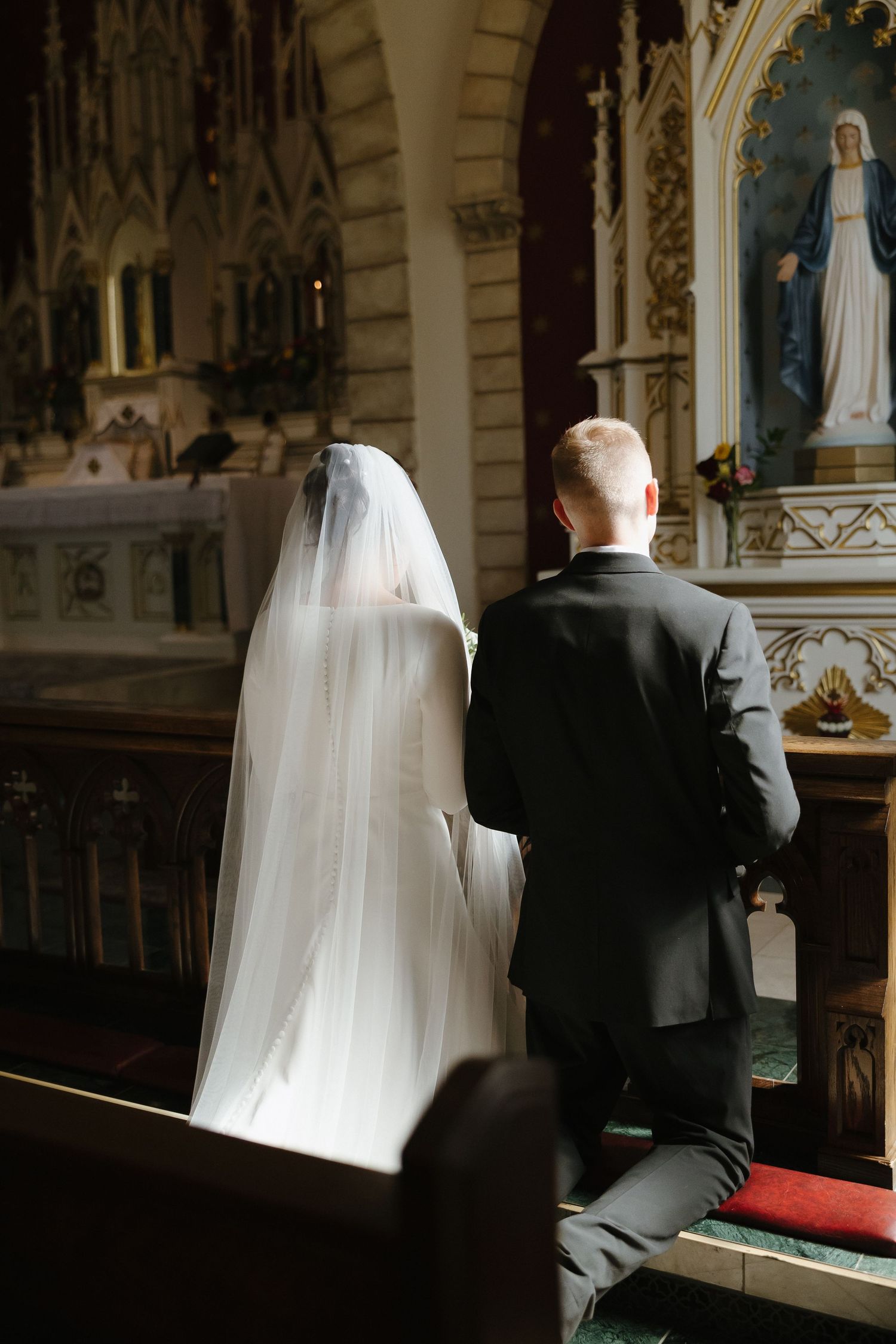 Bride and groom seated in church pews during traditional wedding ceremony.