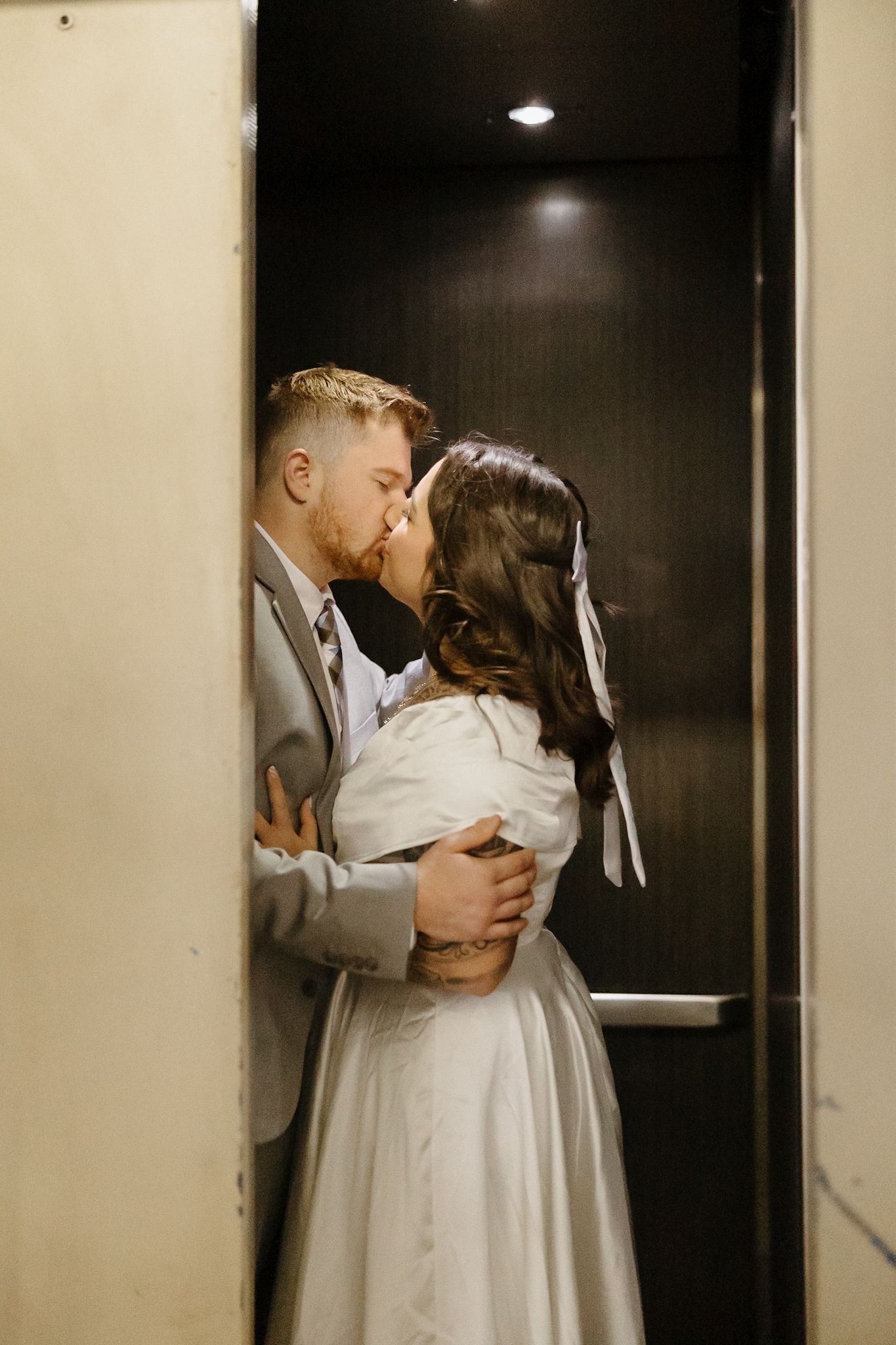 Intimate wedding moment captured in a dimly lit hallway.